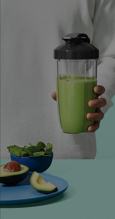 nutribullet blender with fruit and nutes on a green background.