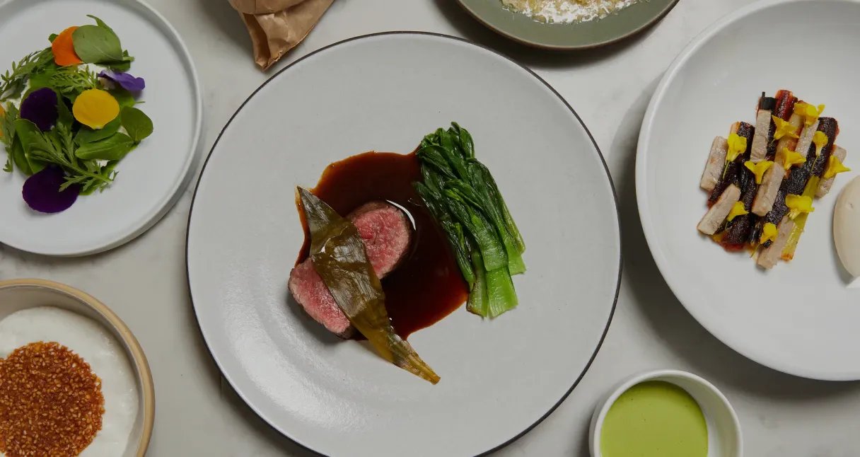 Various white plates of food on a white table.