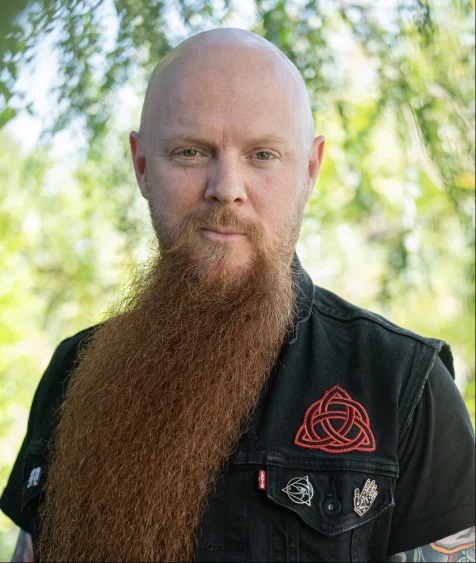 Portrait of a bearded man with a black shirt.