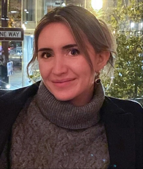 Woman with a gray turtleneck sweater and black jacket.