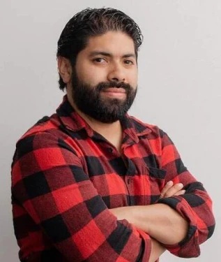 Man with a beard wearing a red and black plaid flannel shirt.