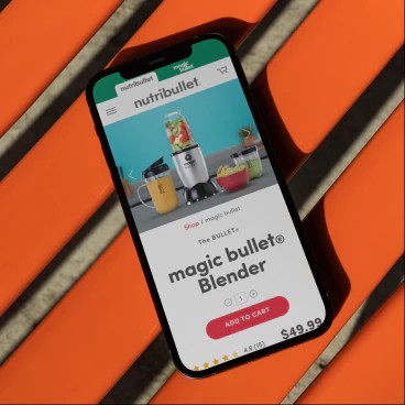 magic bullet website on an iPhone on an orange bench.