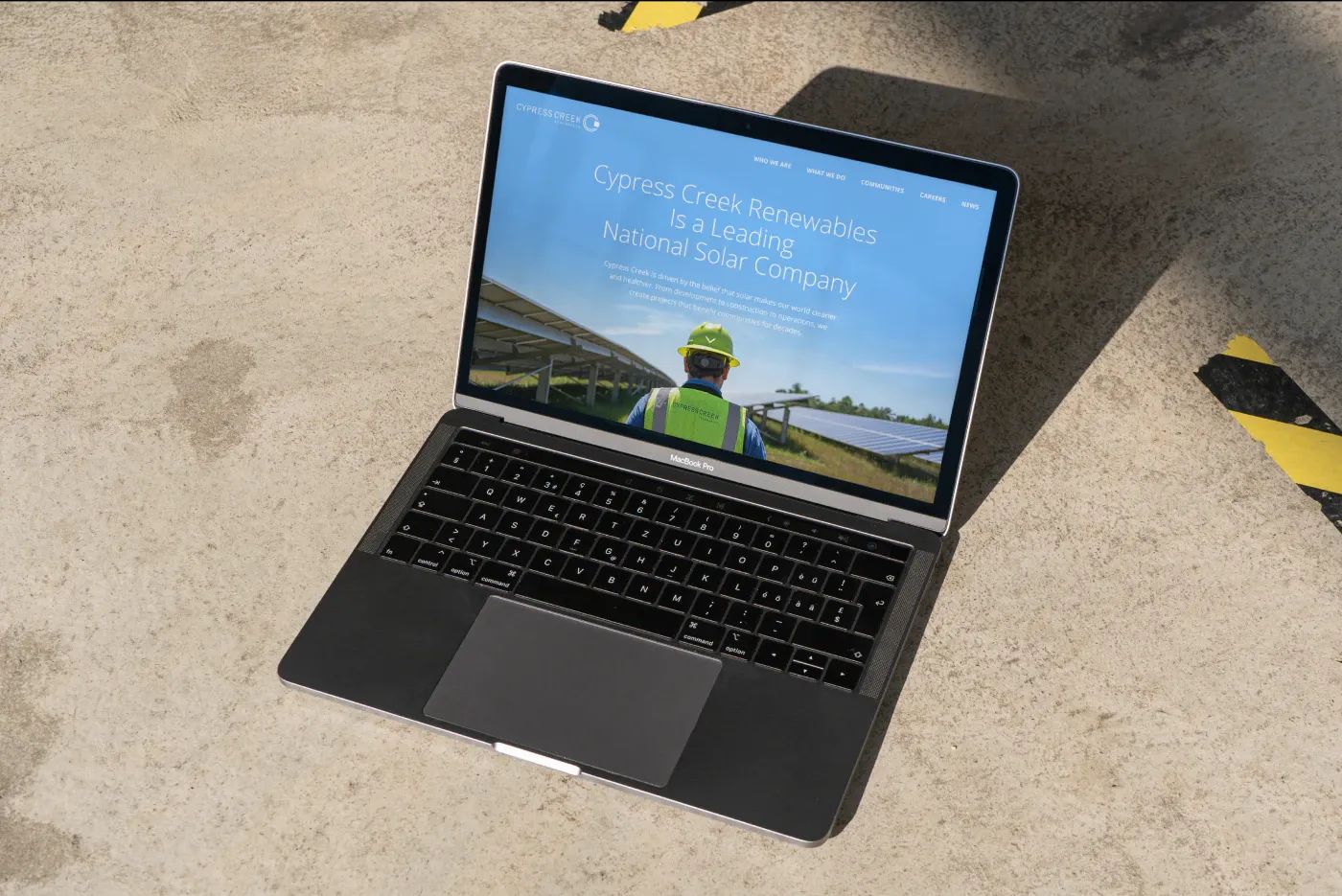 Image of a laptop opened on website on a cement surface.
