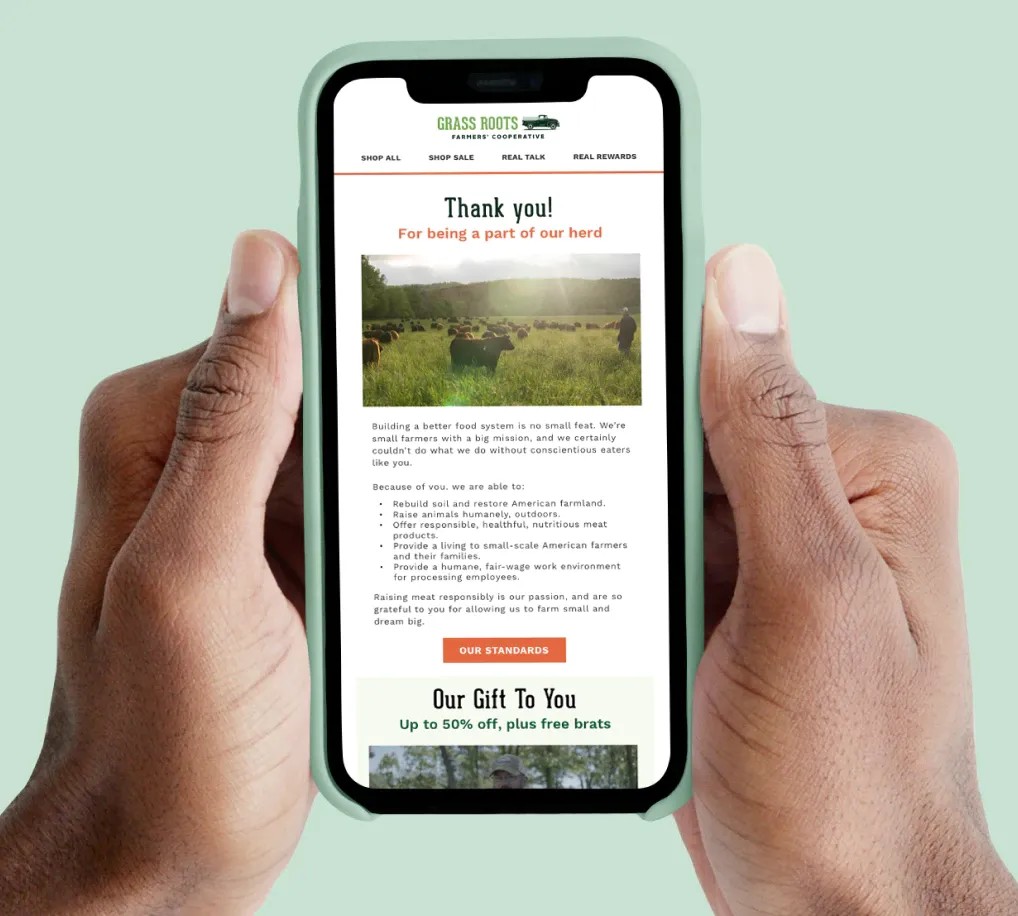 Image of hands holding an iPhone with Grass Roots webpage.