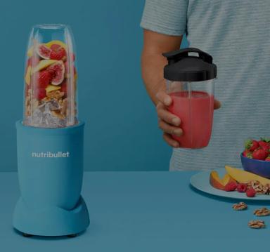 man holding smoothie with nutribullet blender on table