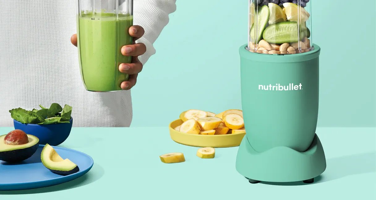 nutribullet blender with fruit and nuts on a green background.